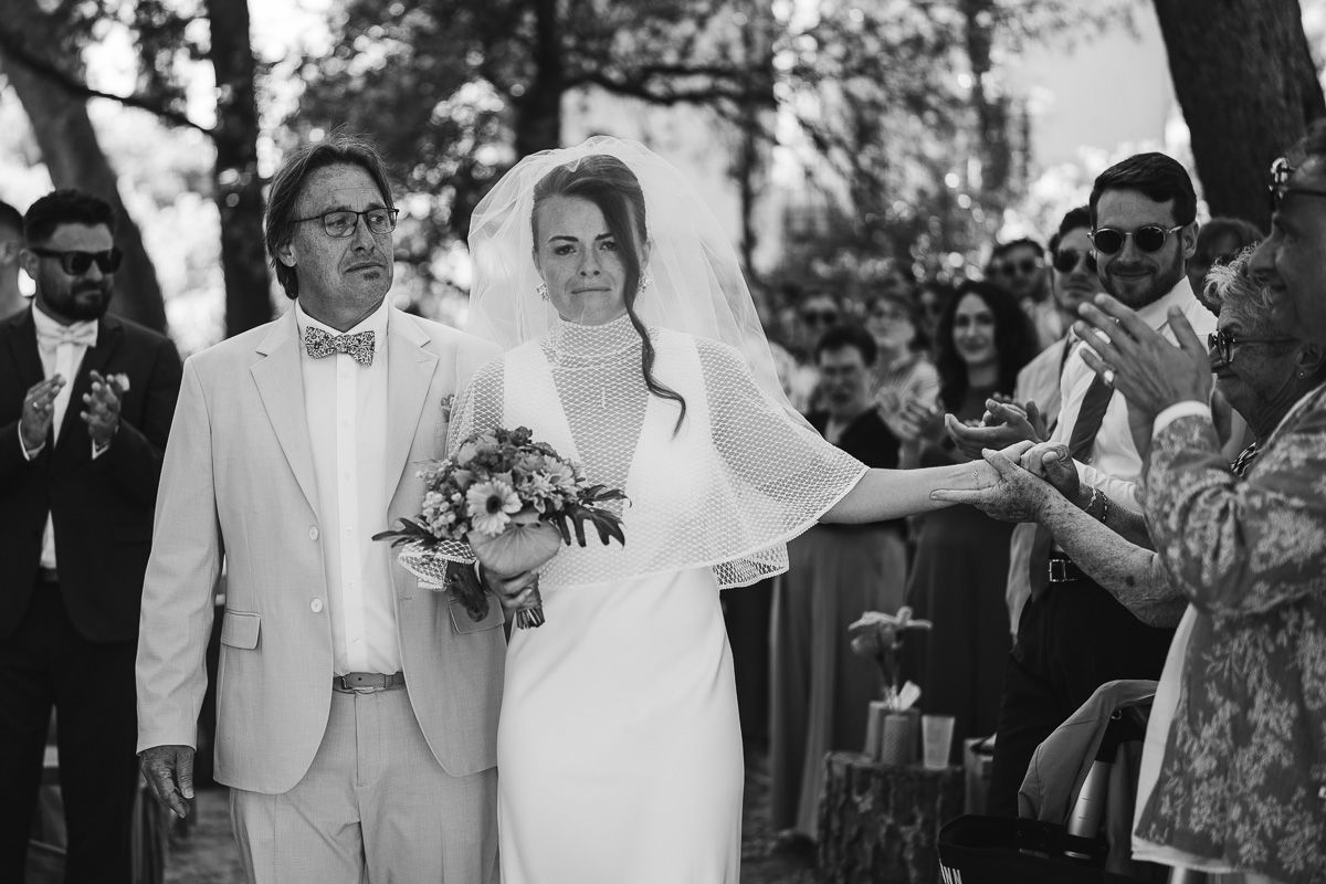 The bride and her father in the aisle, in tears, holding her grandmother's hand