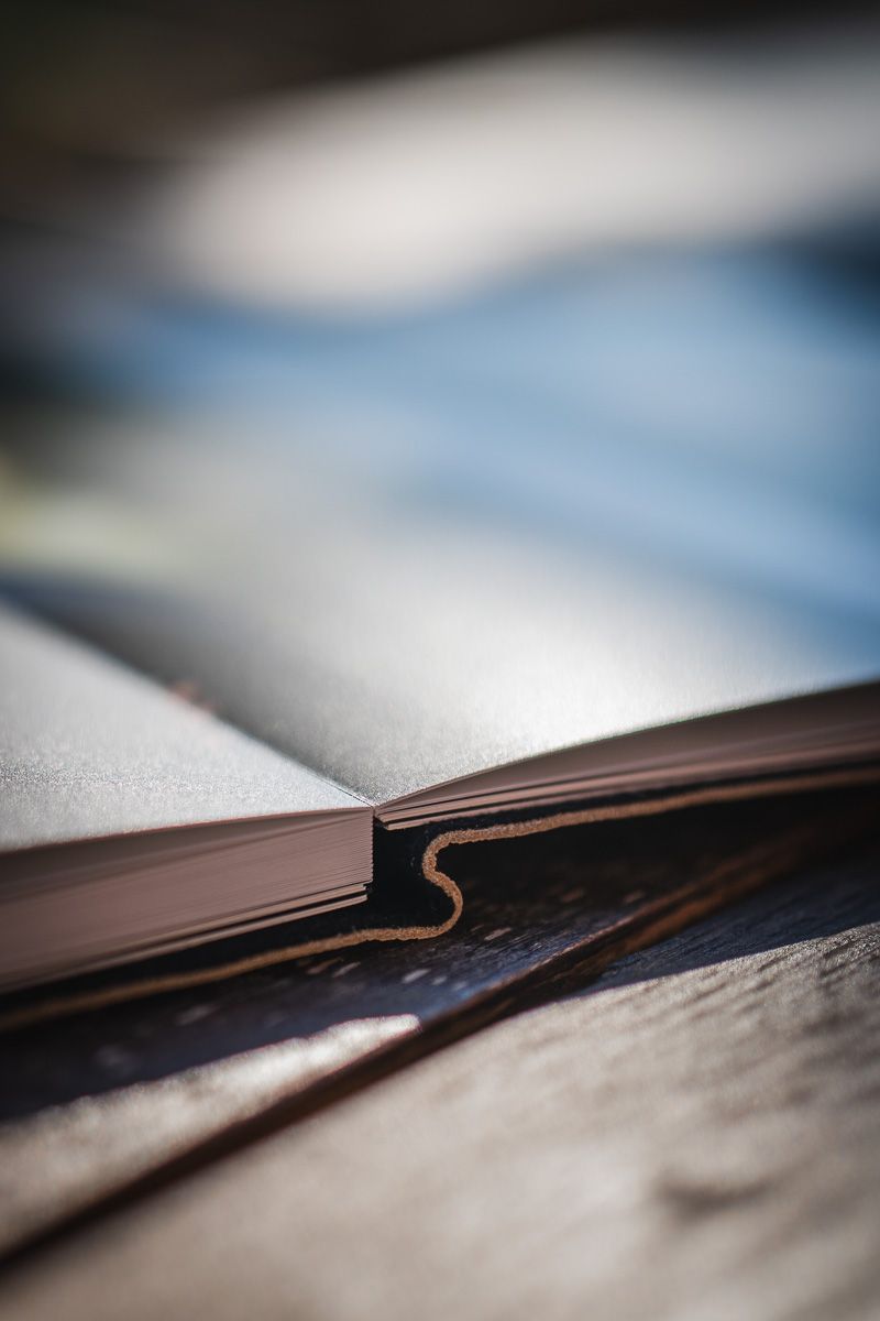 Close-up of an open fine art wedding photo album, hand-sewn leather binding detail — Thibault Maestracci Photographer