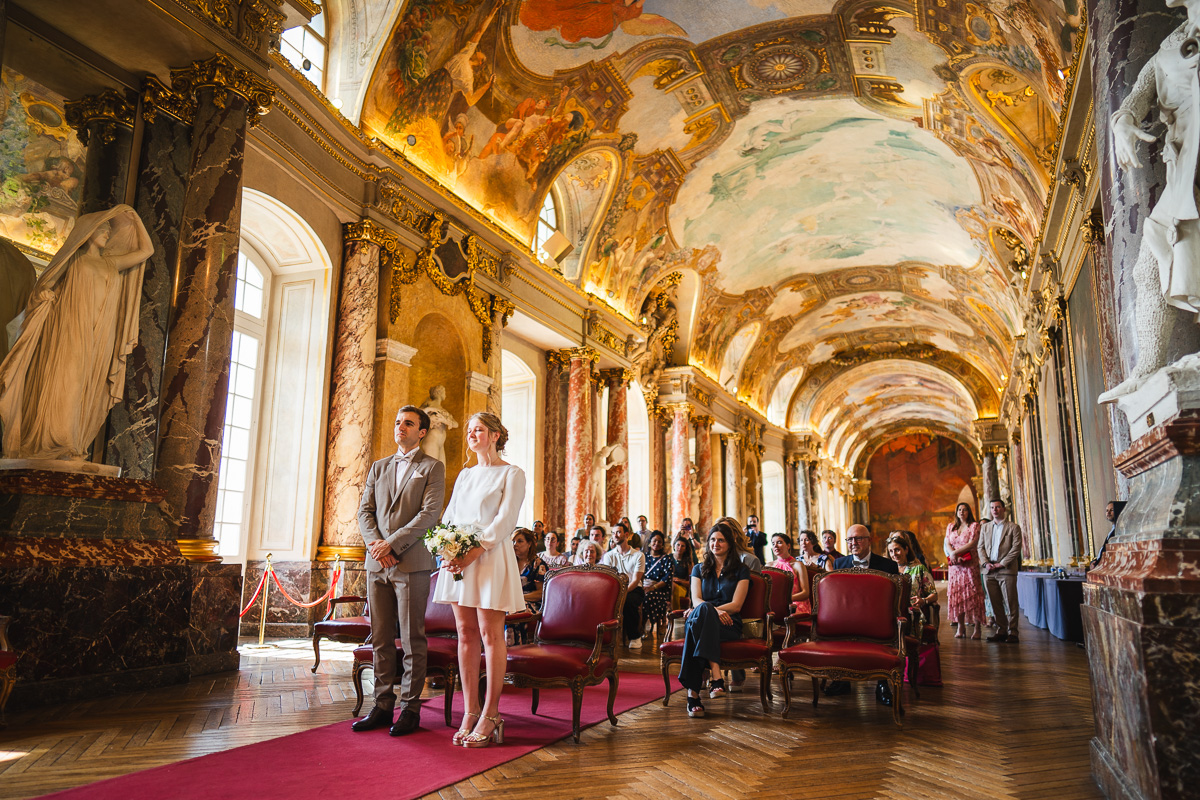 The couple in the foreground during the ceremony in the Salle des Illustres, Capitole de Toulouse