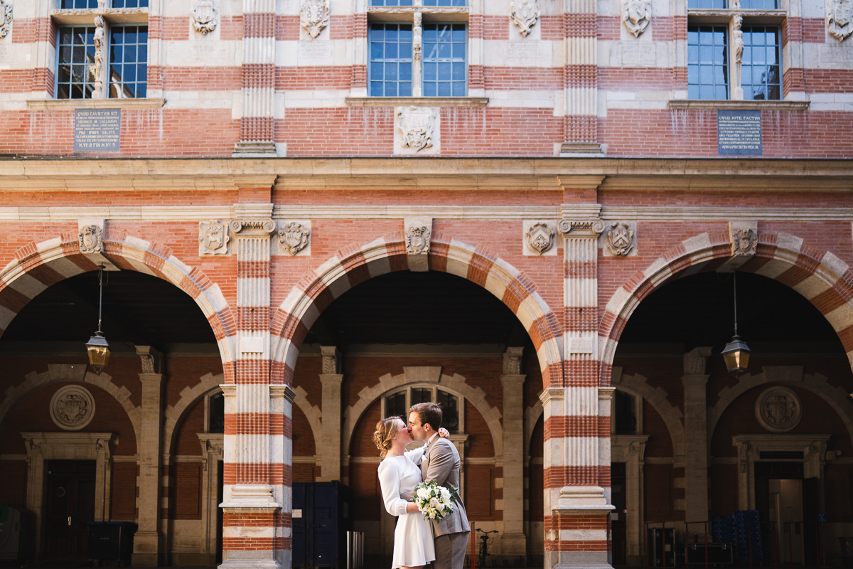 The couple kissing in the courtyard of the Capitole de Toulouse after their ceremony