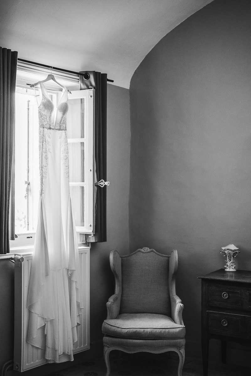 Wedding photographer South of France – black-and-white editorial shot of a bridal dress in backlight by a window in an Occitanie château.