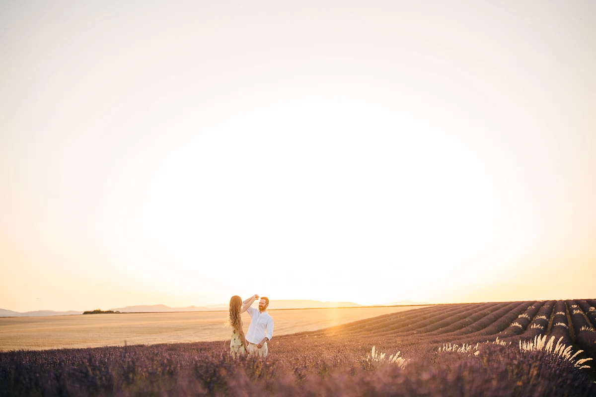 A man twirling his partner in a lavender field at sunset