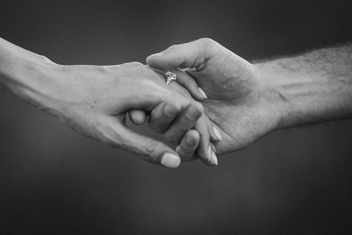 Close-up of joined hands and an engagement ring, black and white