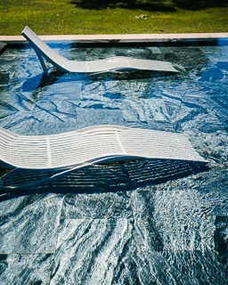 Close-up of the pool at Domaine de la Trinité in Montpellier with white sun loungers and turquoise water
