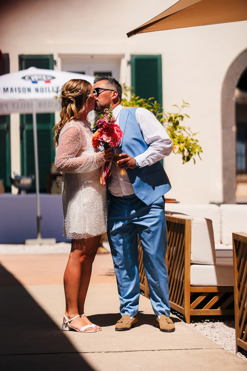 Bride and groom standing together in casual white and blue outfits outdoors