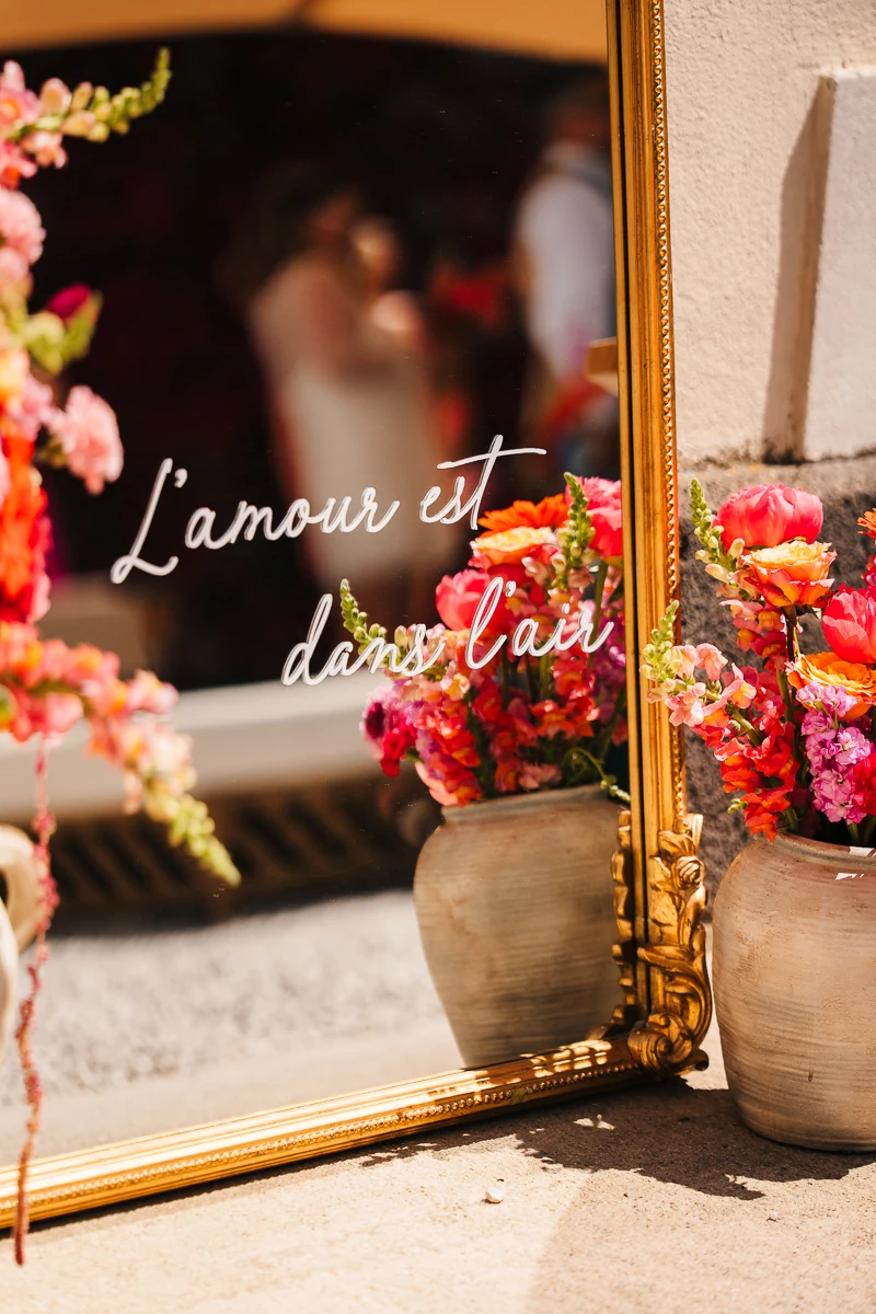 Welcome sign with red flowers by a gold mirror at the wedding venue