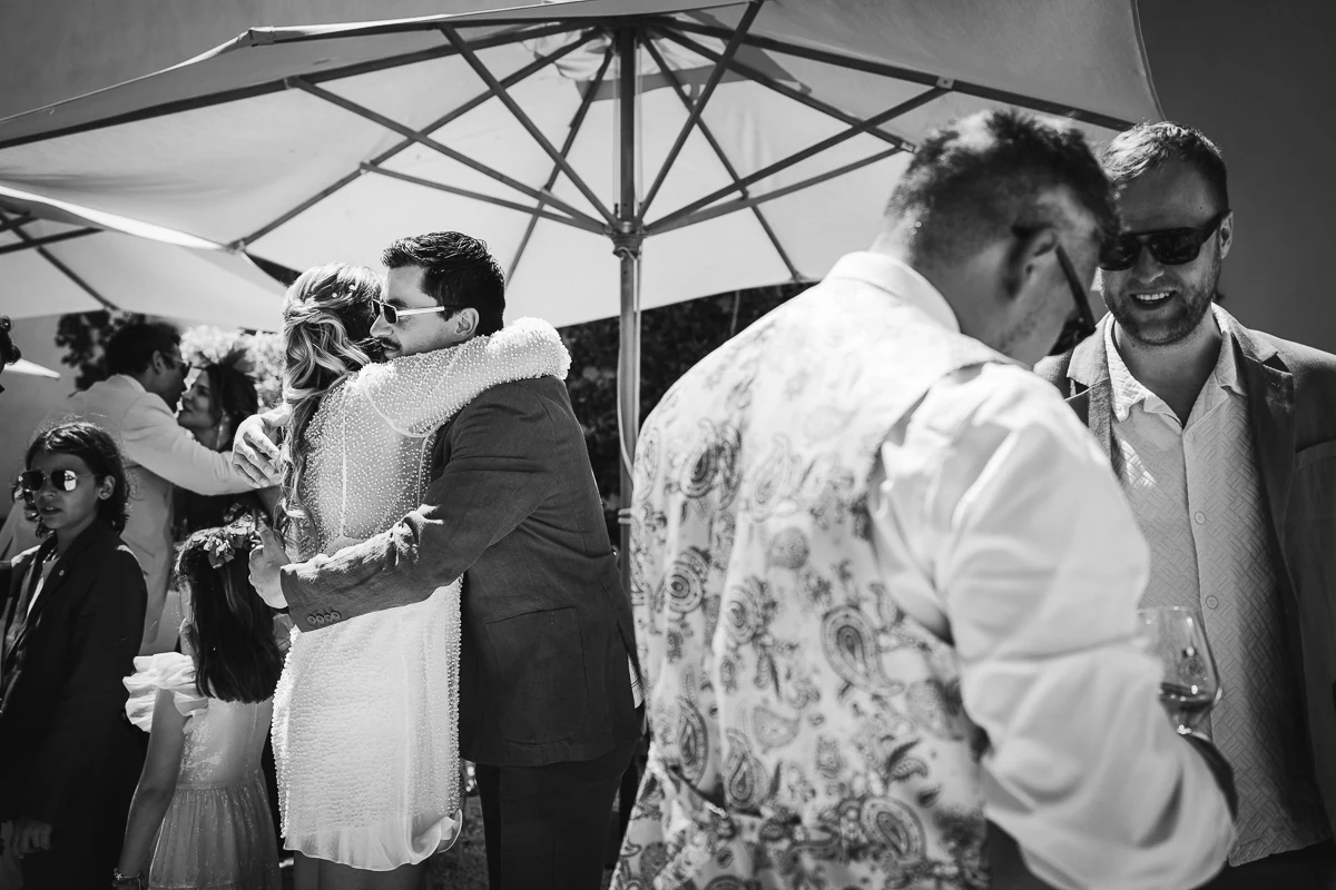 Black and white photo of guests hugging under an umbrella