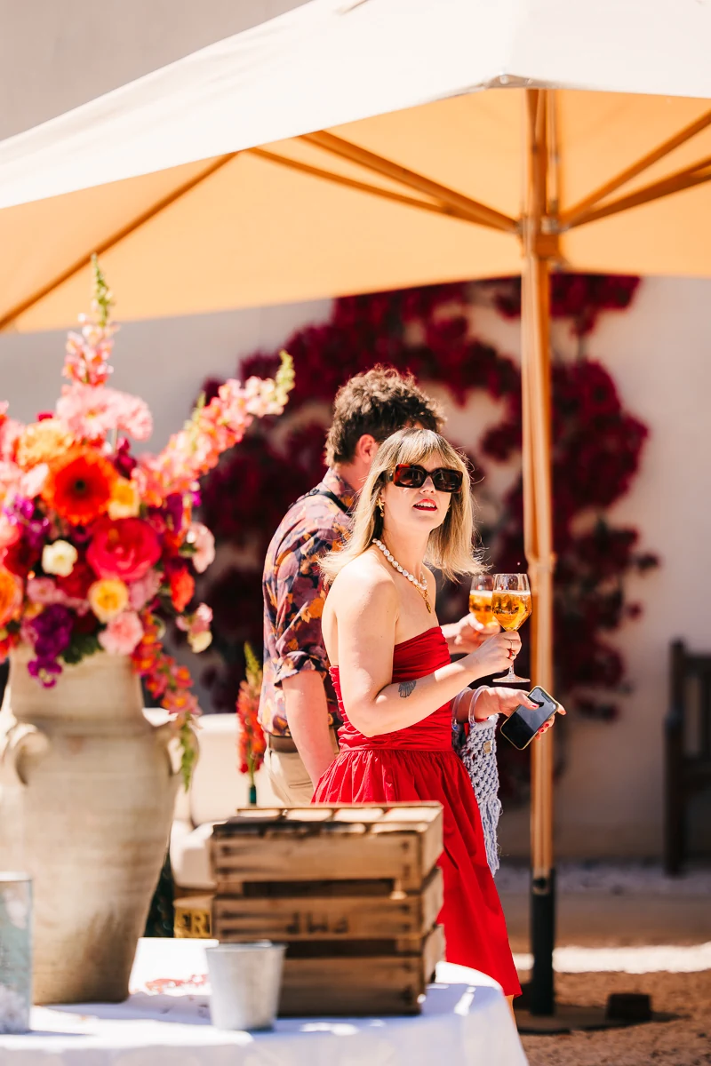 Guests walking through the estate, which is decorated with red flowers, under an orange parasol
