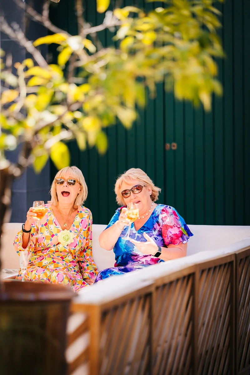 Two women smiling together on a terrace bench