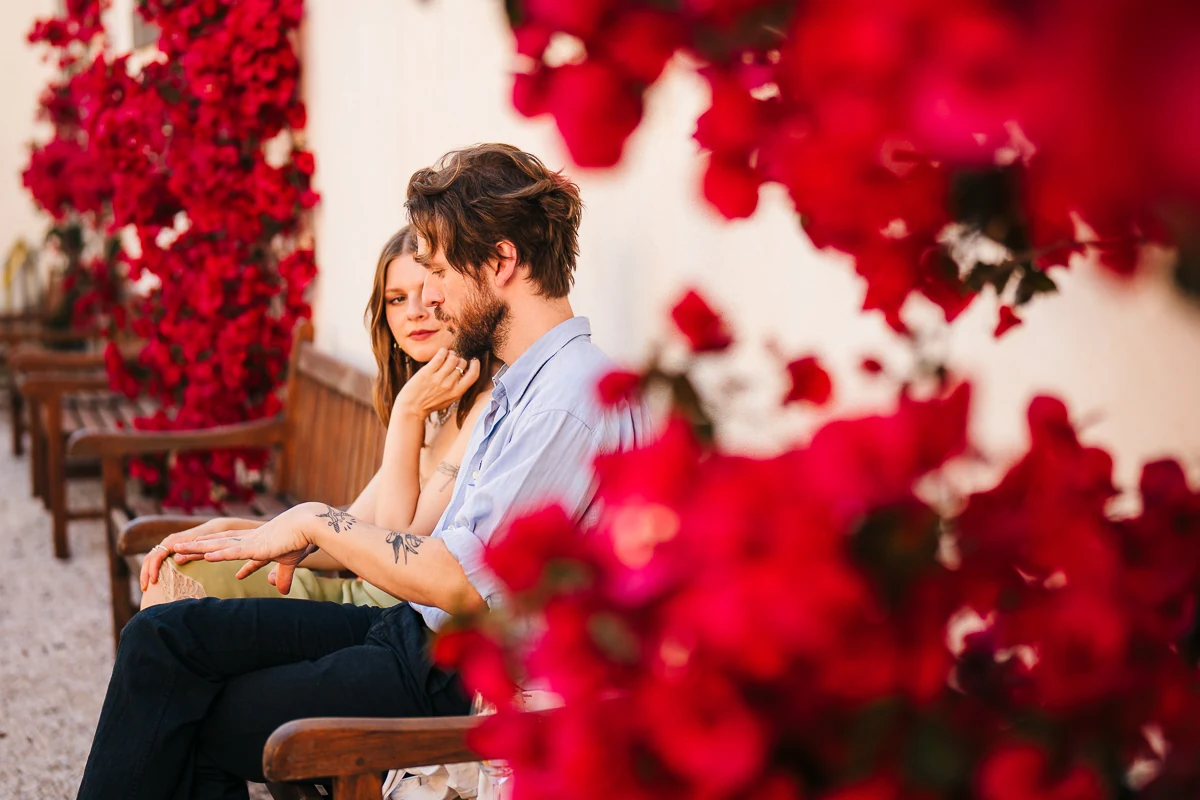 Couple sitting together surrounded by red bougainvillea