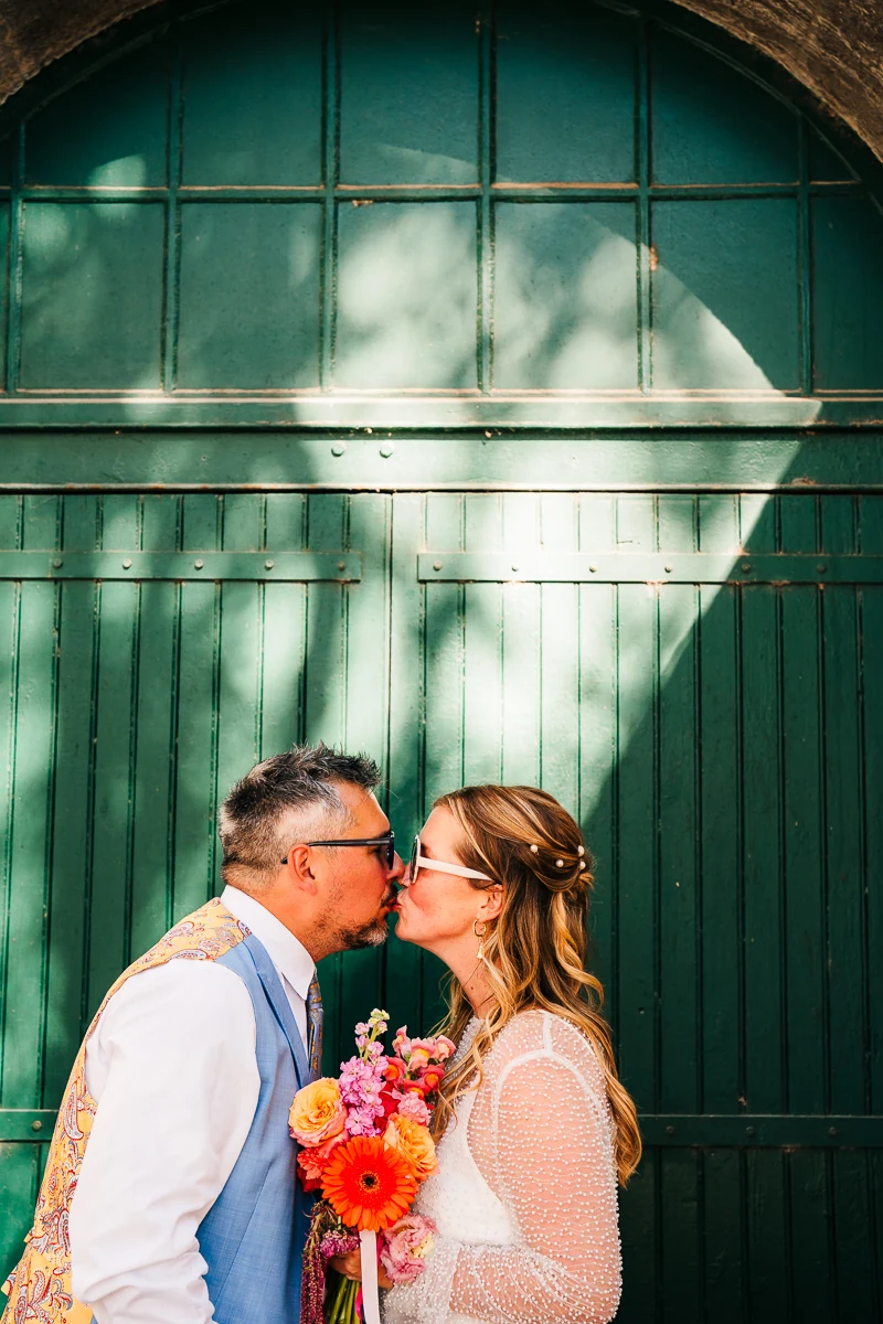 Bride and groom sharing a kiss in front of a green door