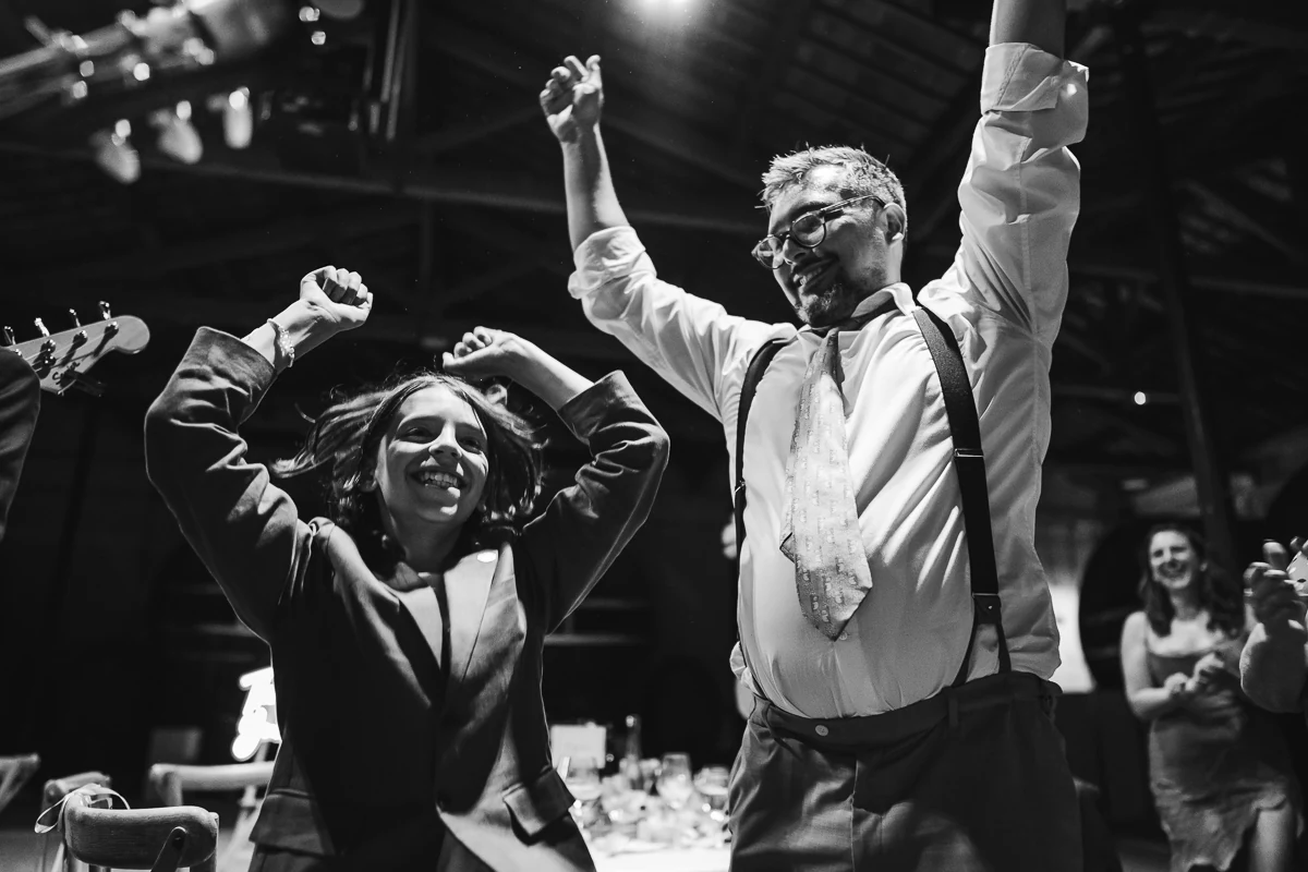 Black and white photo of guests raising their arms while dancing
