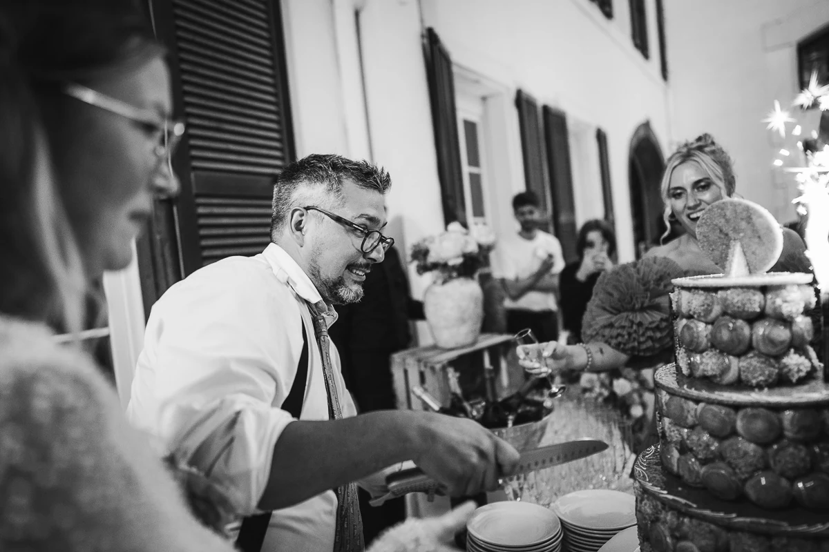 The groom trying to cut the cake as best he can