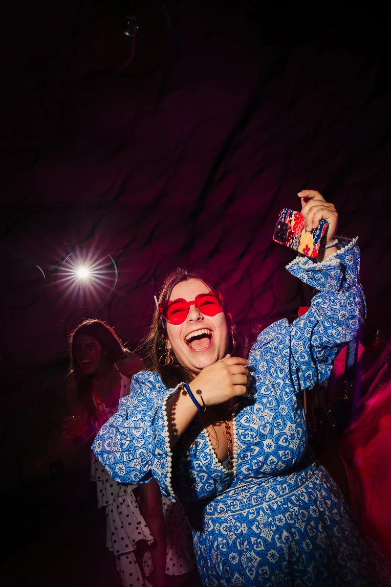 Guests dancing and laughing under red party lights