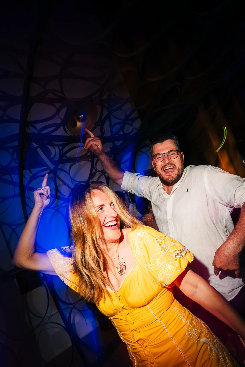 Guests dancing and laughing under blue party lights