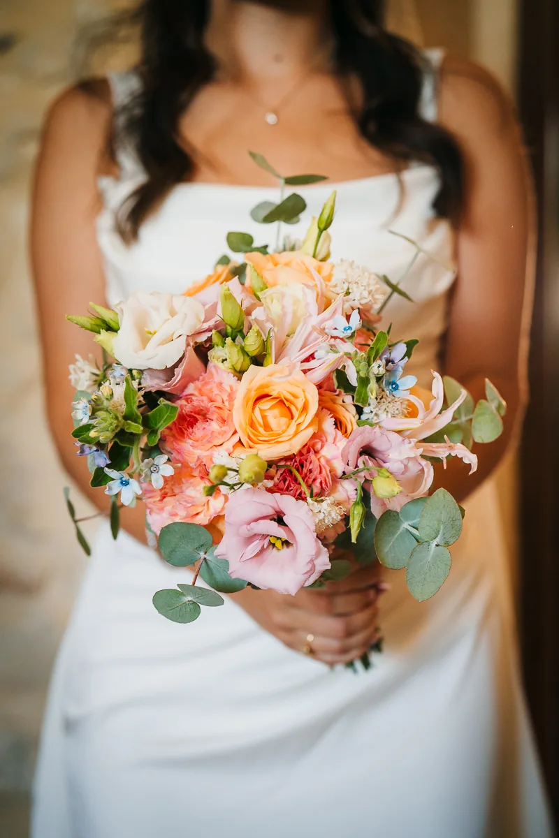 Bride holding a colourful bouquet of peach and pink flowers, Domaine de la Trinité wedding