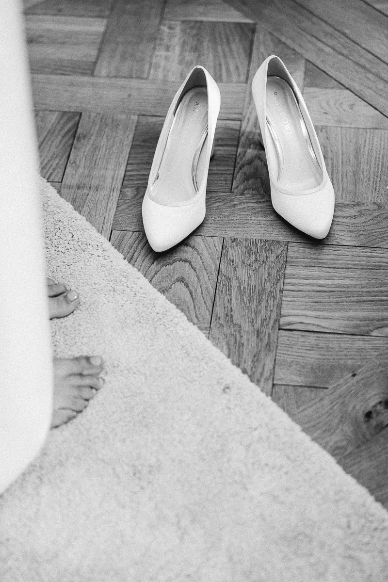 Black and white photo of white bridal shoes on a parquet floor before a wedding in the South of France