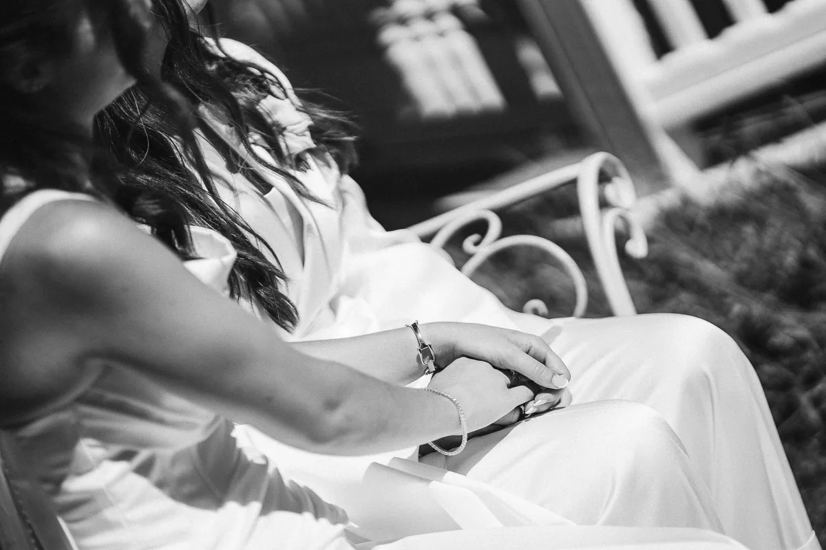 Black and white close-up of two brides holding hands during their wedding ceremony