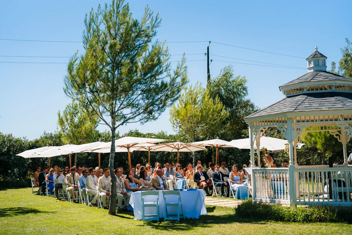 Wedding guests seated on the lawn near the white bandstand for a ceremony at Domaine de la Trinité, Montpellier