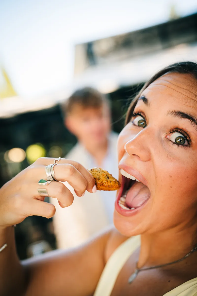 Wedding guest laughing and eating a canapé during the cocktail hour in the South of France