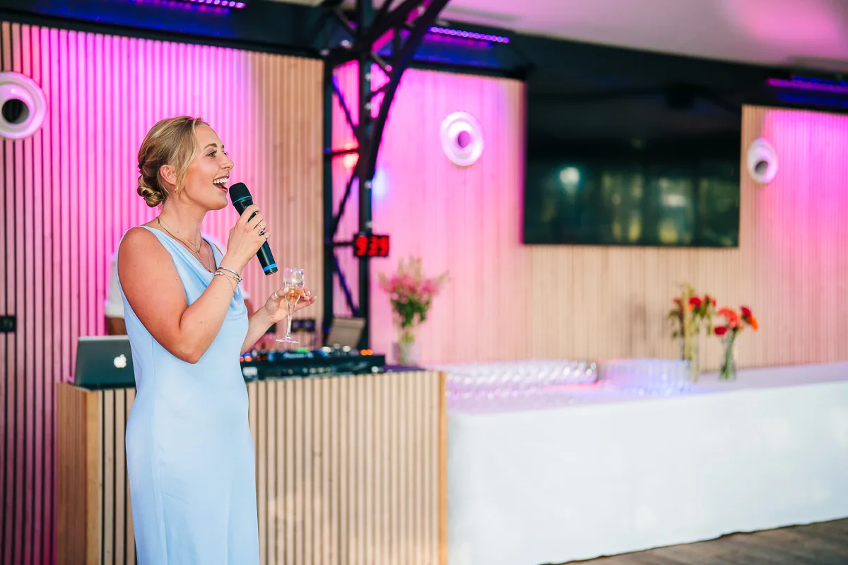 Bridesmaid giving a speech with a microphone in the orangery, Domaine de la Trinité wedding