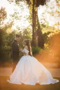 A bride in a white ball gown and a groom in a dark suit hold hands face to face in golden hour light at Domaine de l'Argentière near Montblanc, South of France