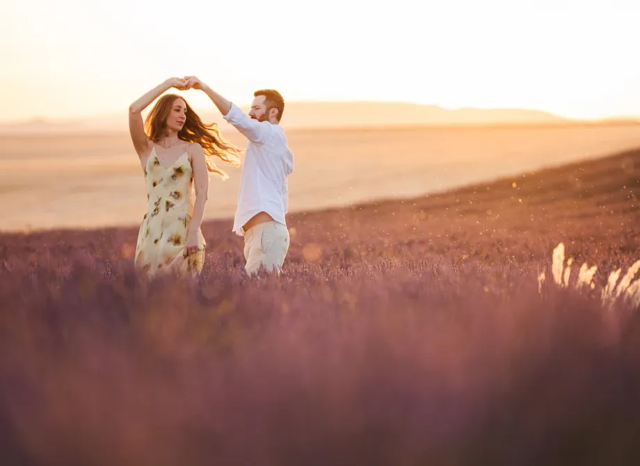 A couple dancing in a lavender field, his hand raised to twirl her
